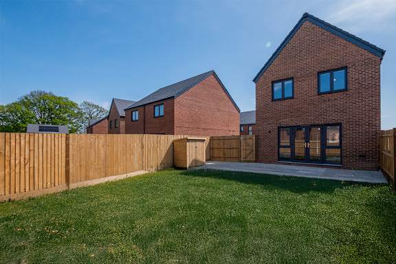 A house with a brown fence and a green lawn.