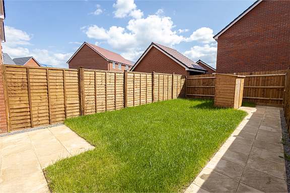 A backyard with a wooden fence and a concrete pathway.