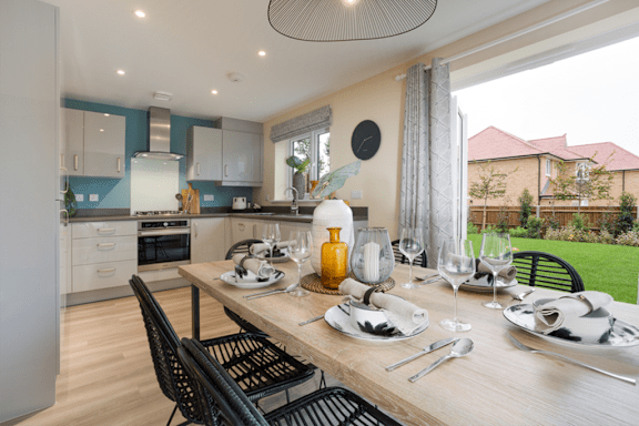 A modern kitchen with a dining table set for two.