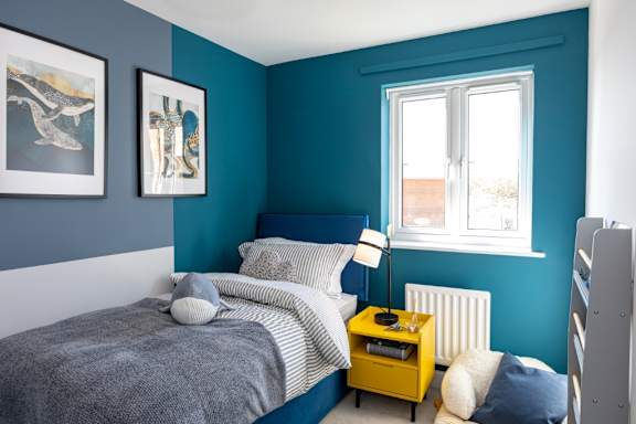 A bedroom with a bed, nightstand, and two framed pictures on the wall.