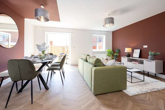 A modern living room with a green sofa and wooden floors.