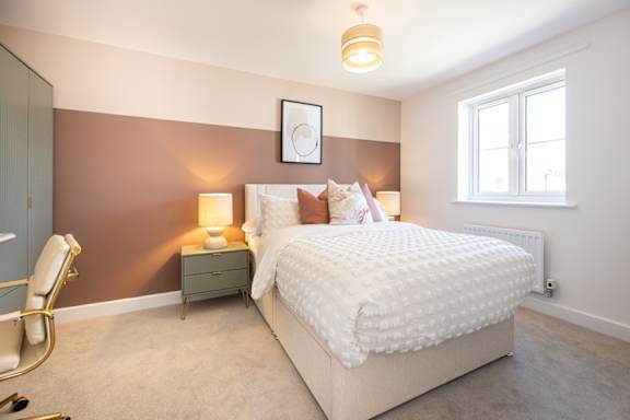 A bedroom with a large bed, a chair, and a window.