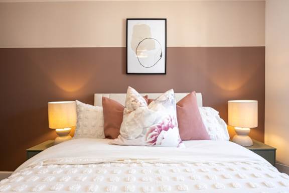 A bed with a white comforter and pink and white pillows is in the image.