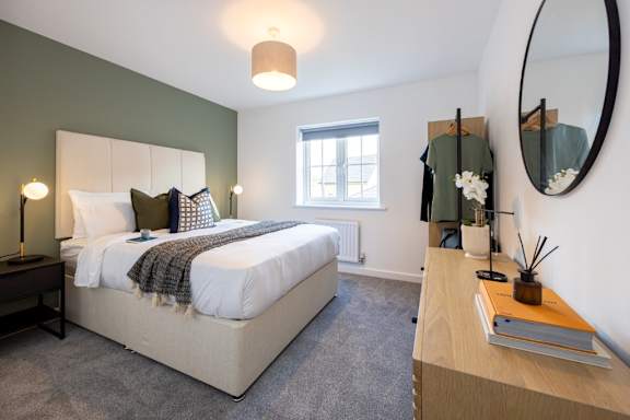 A bedroom with a large bed and a round mirror on the wall.