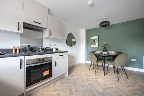 A kitchen with a stove top oven and a dining table with chairs.
