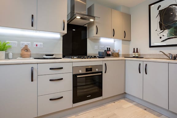 A modern kitchen with white cabinets and a wooden floor.
