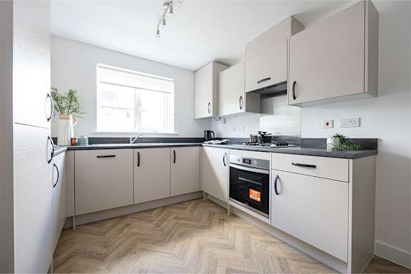 A kitchen with a refrigerator, oven, and cabinets.