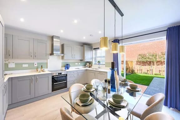 A modern kitchen with a glass dining table set for four.