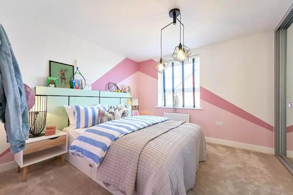 A bedroom with a bed, a nightstand, a window, and a hanging light fixture.
