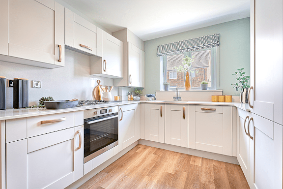 A kitchen with white cabinets and wooden floors.