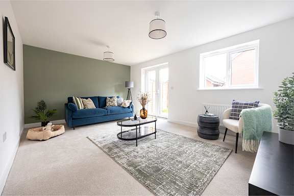 A living room with a blue couch and a grey rug.