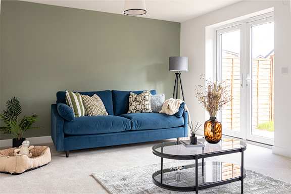 A blue couch with a black metal coffee table in front of it.