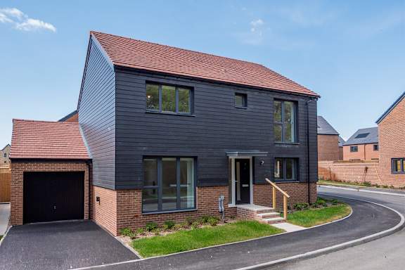 A modern house with a grey exterior and a red roof.