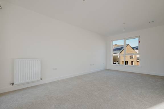 A white room with a window showing a view of a building outside.
