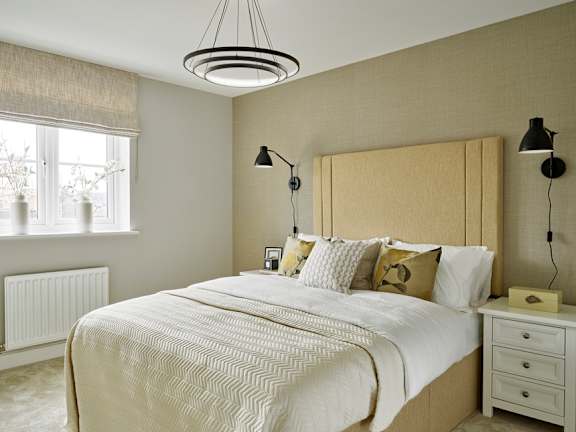 A bedroom with a large bed, two lamps, and a window with curtains.