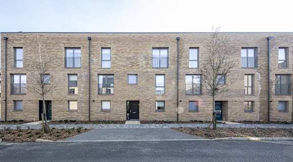 A row of brown brick apartment buildings with black doors and windows.