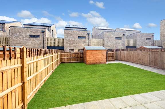 A backyard with a wooden fence and a green lawn.