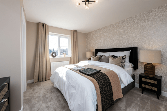 A bedroom with a large bed and a window with curtains.