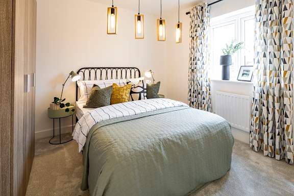 A bedroom with a large bed and a window with curtains.