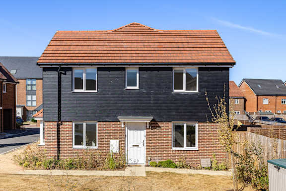 A black house with a red roof and white door.