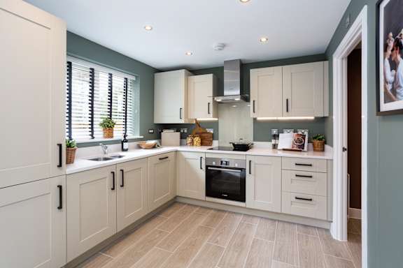 A kitchen with a white refrigerator, sink, and cabinets.