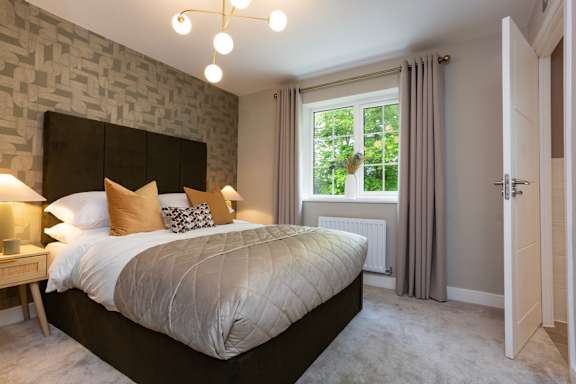 A bedroom with a large bed and a window with curtains.