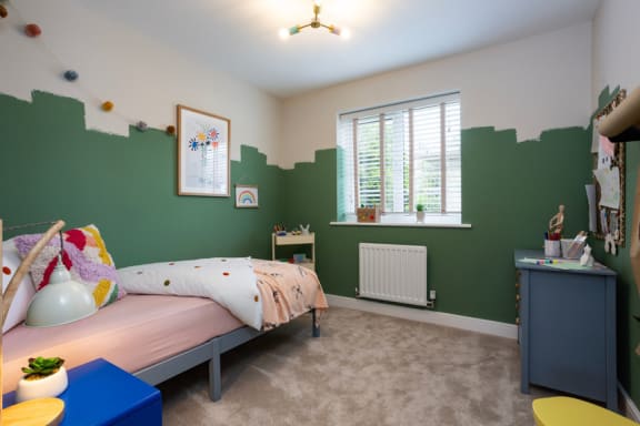 a bedroom with a bed and a green wall and a window