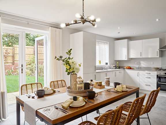 A dining table set with chairs and a vase of flowers.