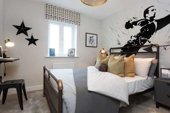 A bedroom with a bed, nightstand, and a wall mural.