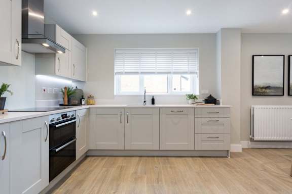 A modern kitchen with wooden floors and white cabinets.