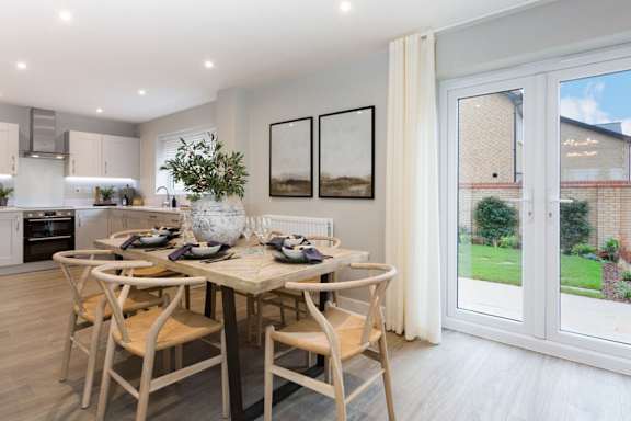 A dining room with a table set for two and a view of a backyard through a sliding glass door.
