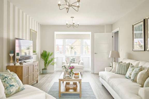 A living room with a white couch, a wooden cabinet, a coffee table, and a chandelier.