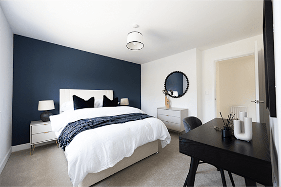A bedroom with a white bed and a black table.