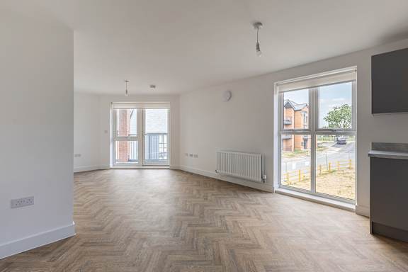 A room with wooden flooring and white walls.