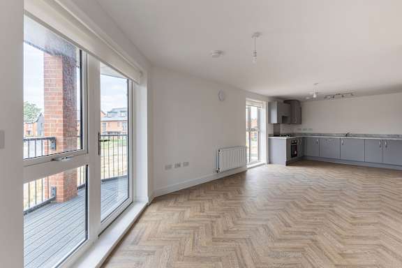 A spacious room with wooden flooring and a large window.