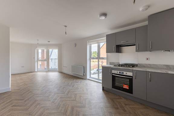 A kitchen with a stove top oven and a wooden floor.