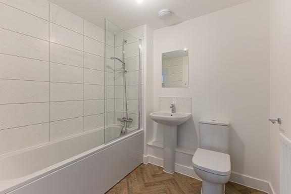A white bathroom with a toilet, sink, and bathtub.