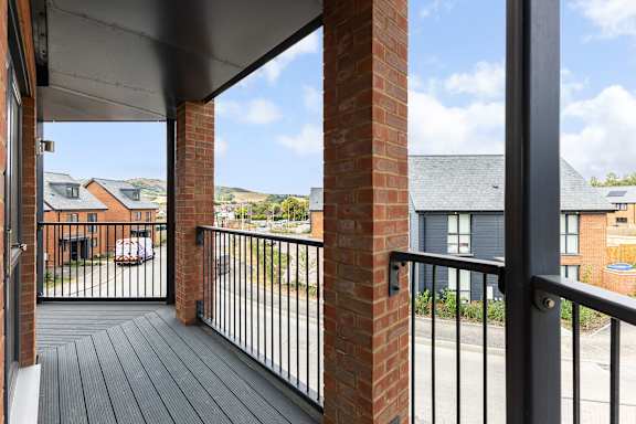 A balcony with a black railing and a brick pillar.