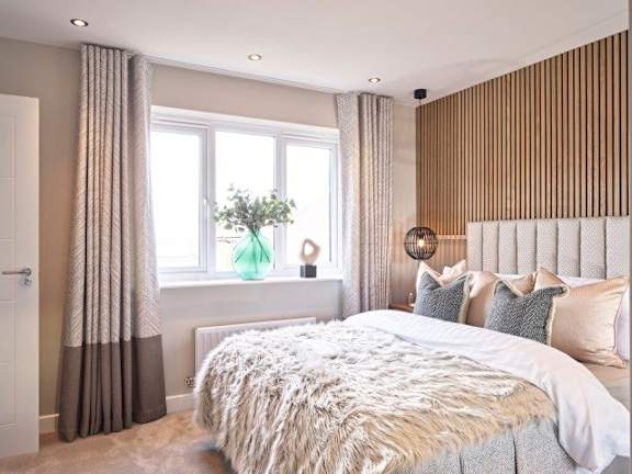 A bedroom with a large bed and a window with curtains.
