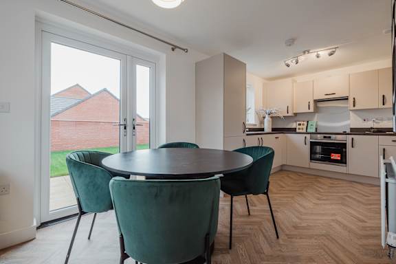 A kitchen with a table and chairs in front of a sliding glass door.