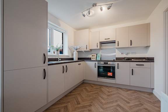 A kitchen with wooden flooring and white cabinets.