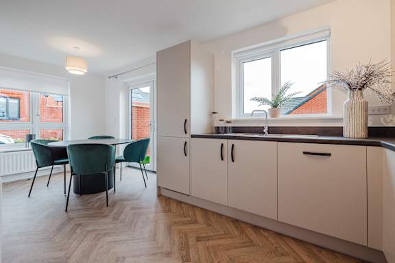 A kitchen with a table and chairs in front of a window.