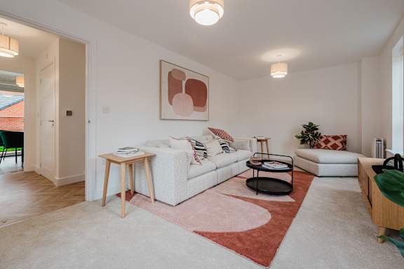 A living room with a white couch and a red rug.