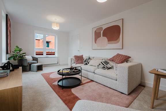 A living room with a grey couch and a red rug.