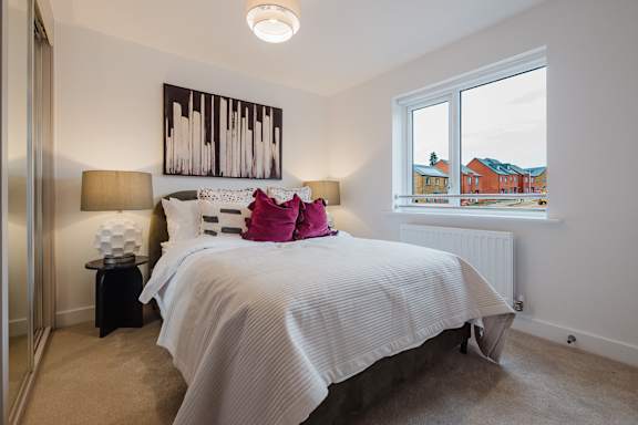 A bedroom with a large bed and a window overlooking a residential area.