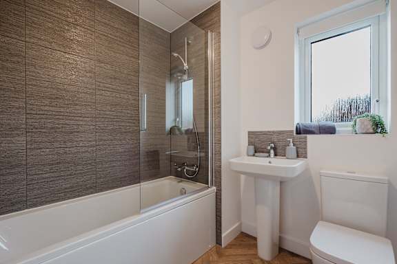 A bathroom with a white tub, sink, and toilet.