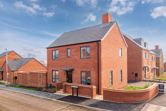 A red brick house with a black roof and a driveway in front.