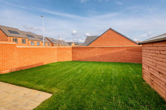A backyard with a green lawn and a brick wall.