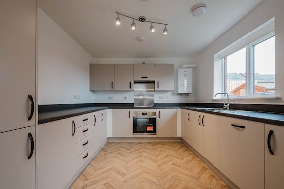 A modern kitchen with white cabinets and a wooden floor.