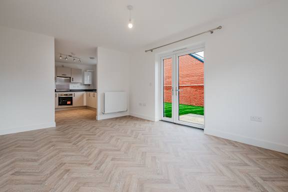 A room with a herringbone patterned floor and a sliding door leading to a backyard.